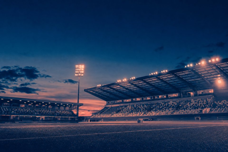 Belgisch voetbalstadion bij avond, gezien vanaf de tribune