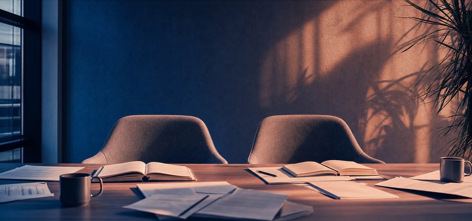 Twee lege stoelen aan een redactietafel met opengeslagen notitieboeken