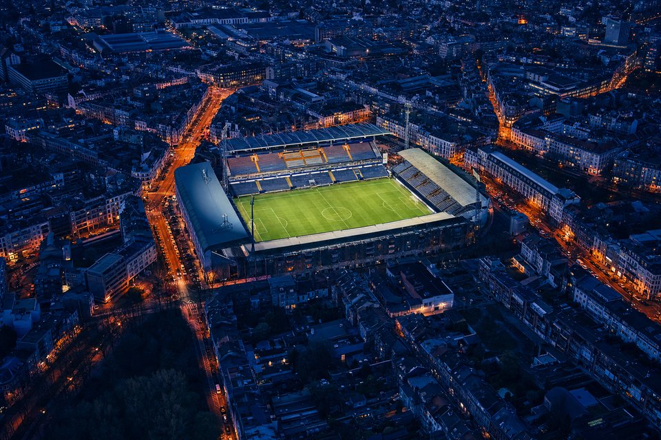 Belgisch stadion ingesloten door stadsbebouwing, gezien in het blauwe uur
