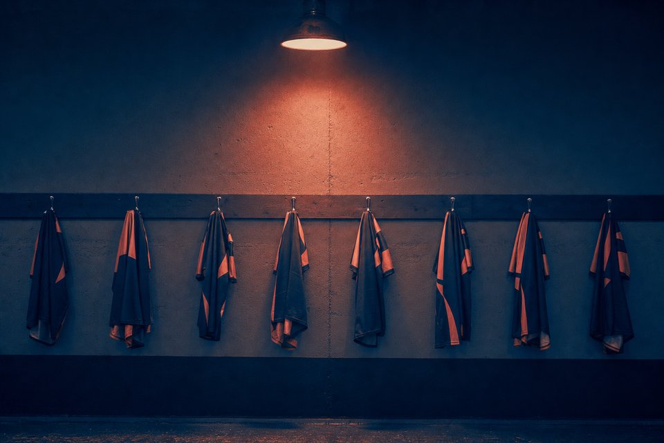 Wedstrijdshirts op een rij haken in een schemerige spelerstunnel