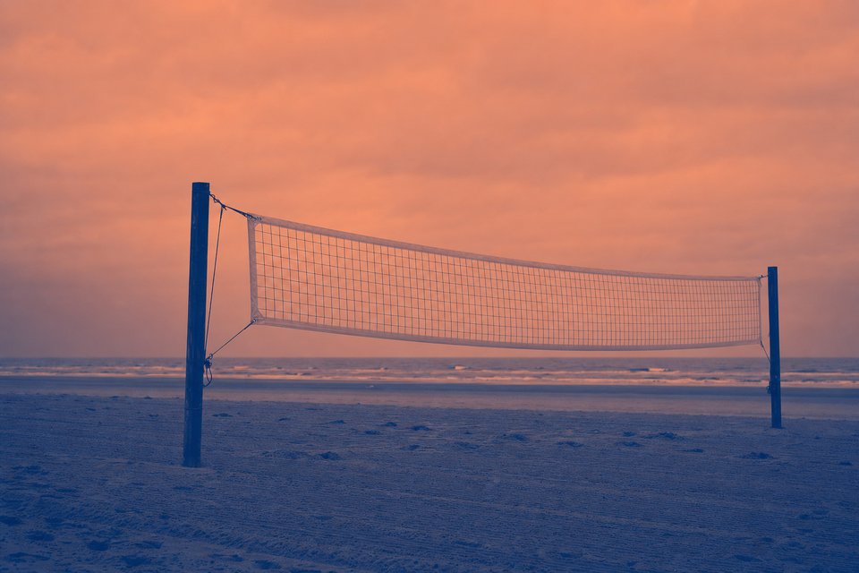 Beachvolleybalnet en geharkt zand aan de Noordzeekust bij bewolkt weer