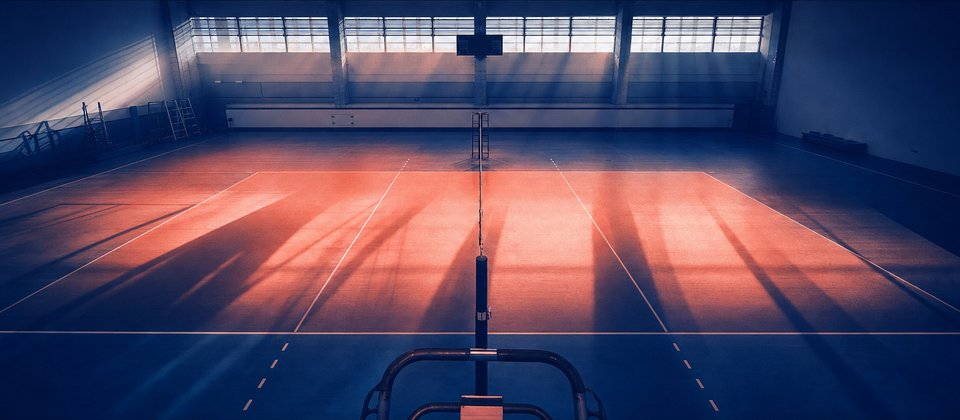 Volleybalveld in een sporthal met ochtendlicht door hoge ramen