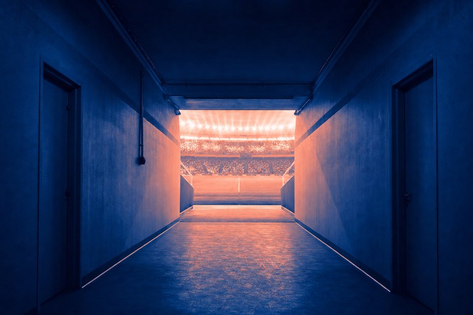 Spelerstunnel van een stadion met uitzicht op het verlichte veld
