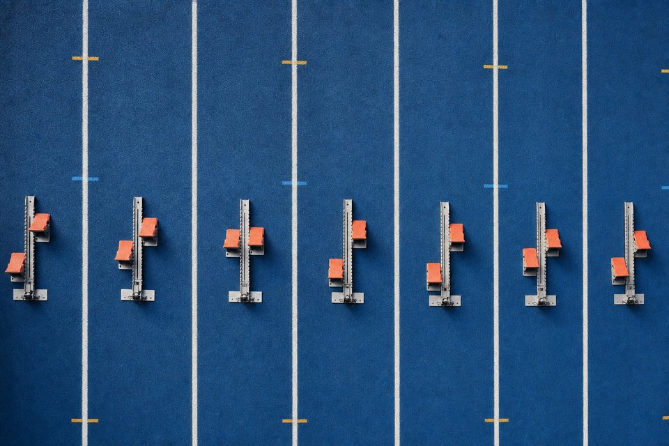 Startblokken op een blauwe atletiekbaan, recht van boven gezien